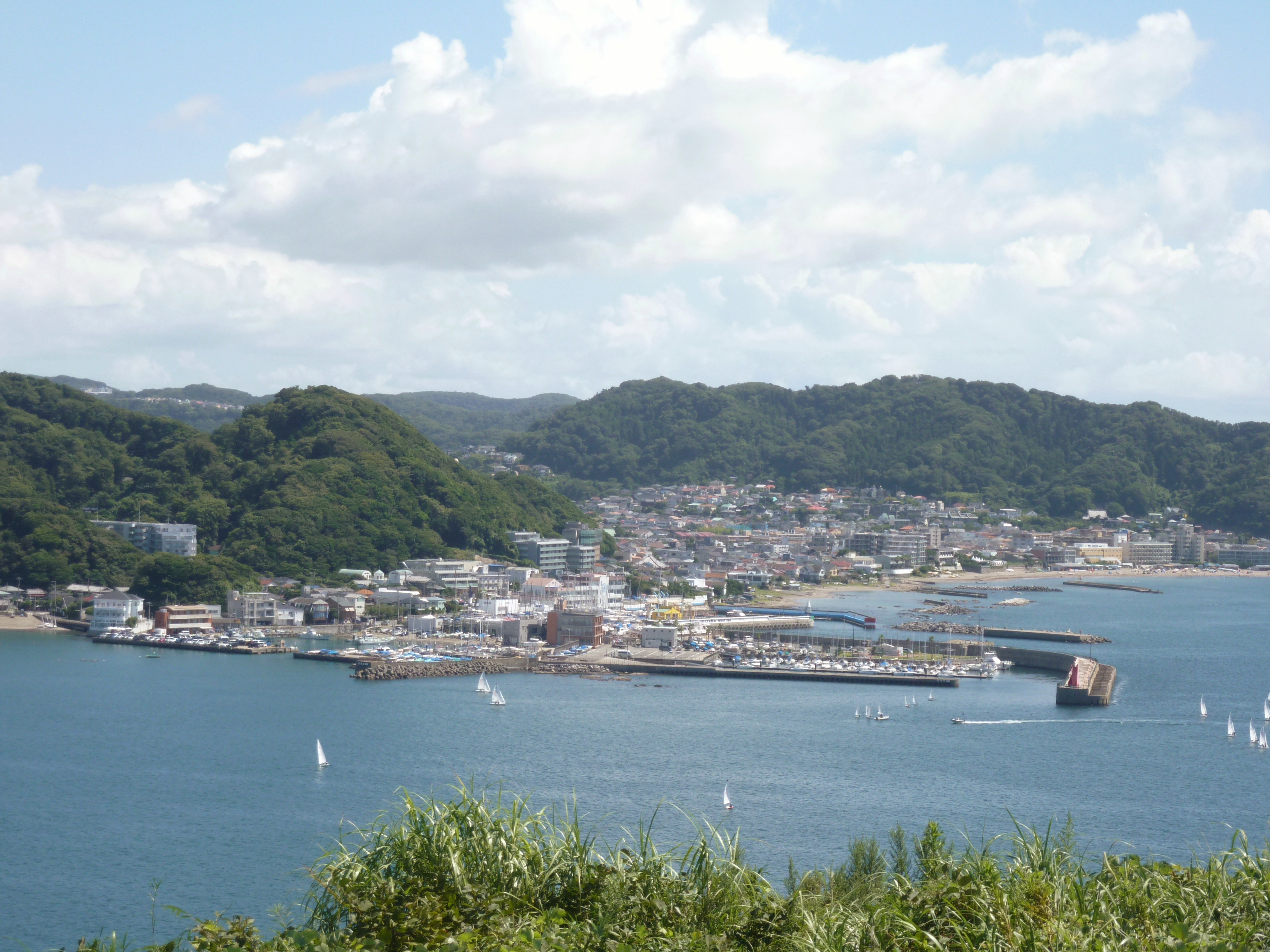 ヨットが浮かぶ葉山港と、山あいに広がる町並み
